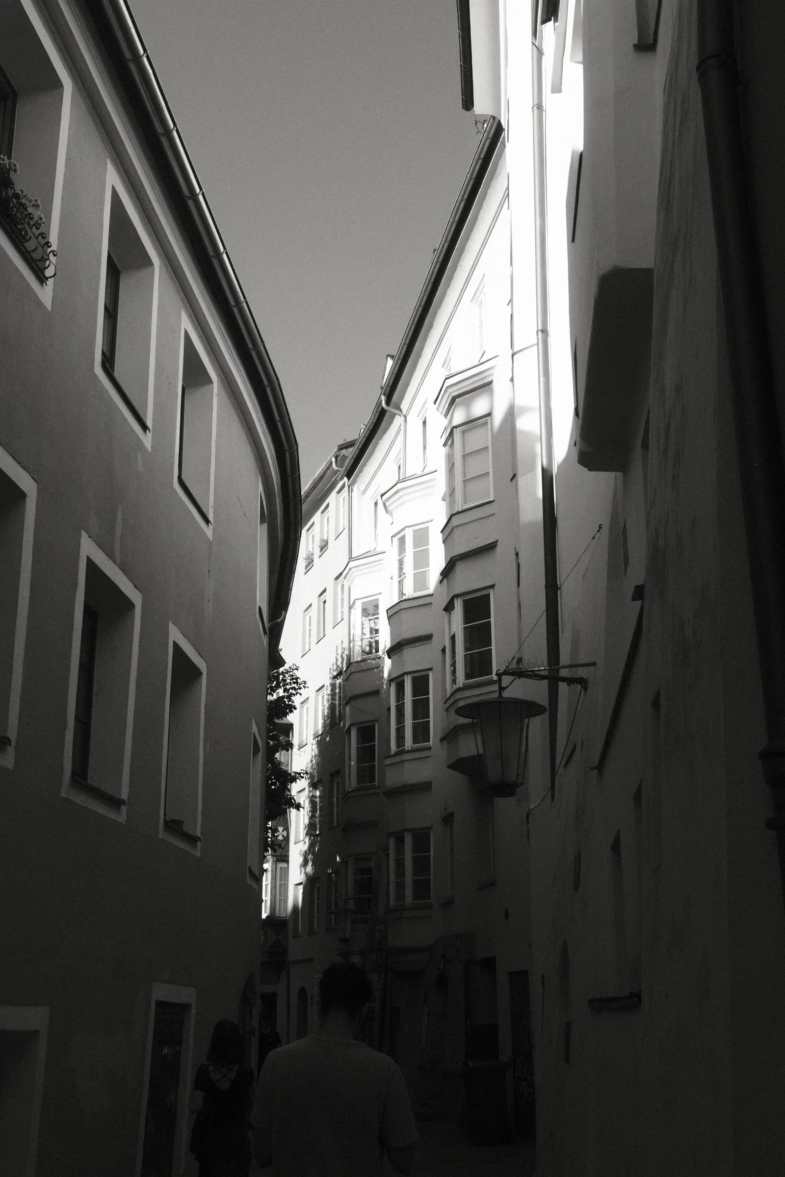 People walking through a bright archway in a black and white street photograph